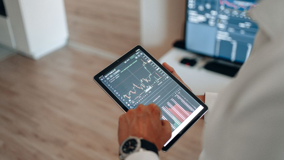 Prikaz ruku koje koriste tablet za online trgovanje i analizu tržišta